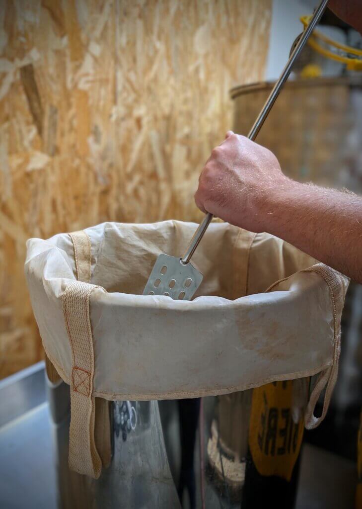 main en train de mélanger dans une cuve de brassage