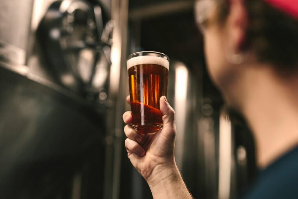 brasseur observant un verre de bière qu'il tient dans sa main