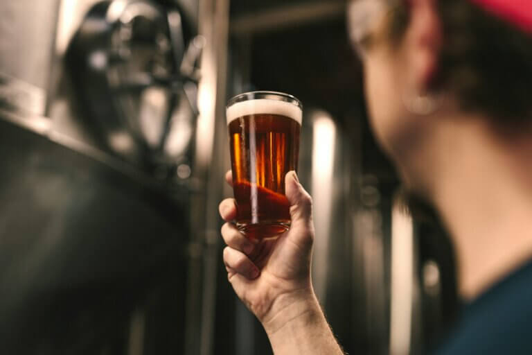brasseur observant un verre de bière qu'il tient dans sa main